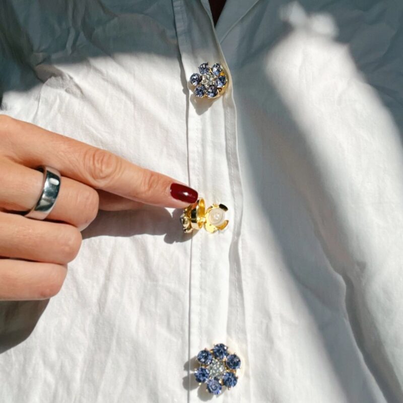 Named after the founder’s oma Hildegard, Hilde combines softness, elegance and personality in one refined accessory.Unlike traditional brooches or pins, these button charms simply click onto existing buttons up to 13 mm wide. No sewing and no permanent changes — just an effortless way to elevate shirts, blazers, cardigans or jackets within seconds.And honestly? They feel less like accessories and more like jewellery for your clothes.